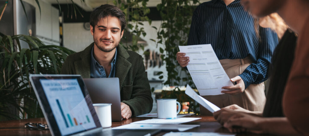 Zwei Freelancer arbeiten konzentriert an neuen Projekten in einem modernen Büro, umgeben von Laptops, Notizen und Kaffee.