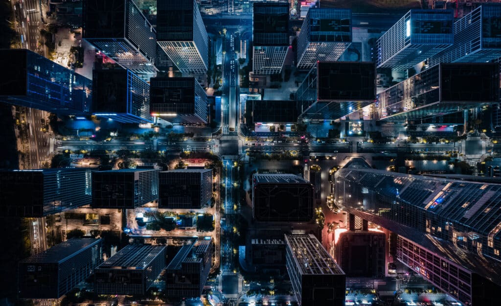 Stadtansicht bei Nacht aus der Vogelperspektive mit beleuchteten Wolkenkratzern und Straßen. Verkörpert Energie und Strom.
